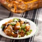 Taco tater tot casserole on a plate with the casserole dish in the background.