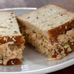 Chipotle tuna salad sandwich on a plate and cut in half.