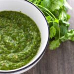 Easy chimichurri sauce with roasted garlic and some fresh parsley on a table.
