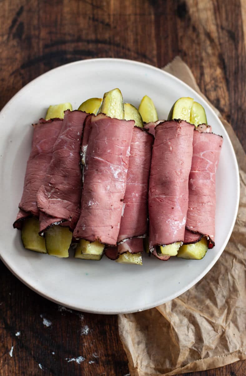 A white plate piled with pickle roll-ups.
