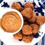 Pile of chorizo sausage balls on a plate next to a dipping sauce.