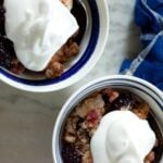 Little bowls of blackberry crisp topped with whipped cream.