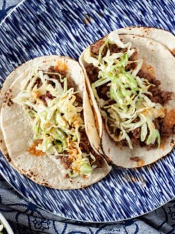Ground venison tacos topped with slaw on a plate.