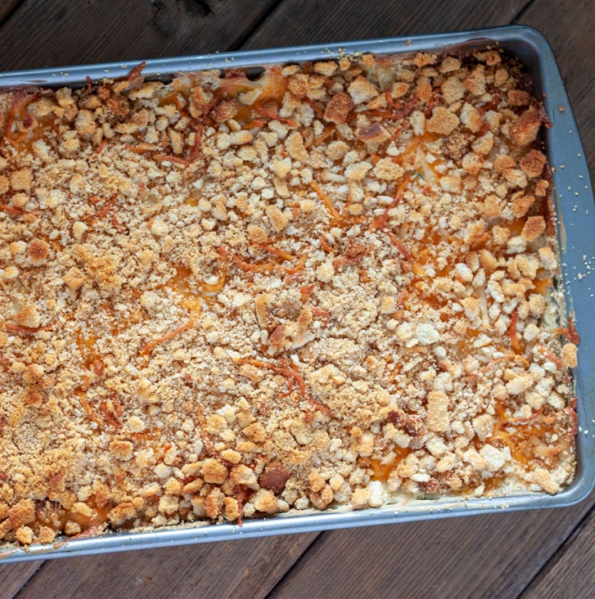 Cheesy potato casserole with crouton topping in a baking pan.