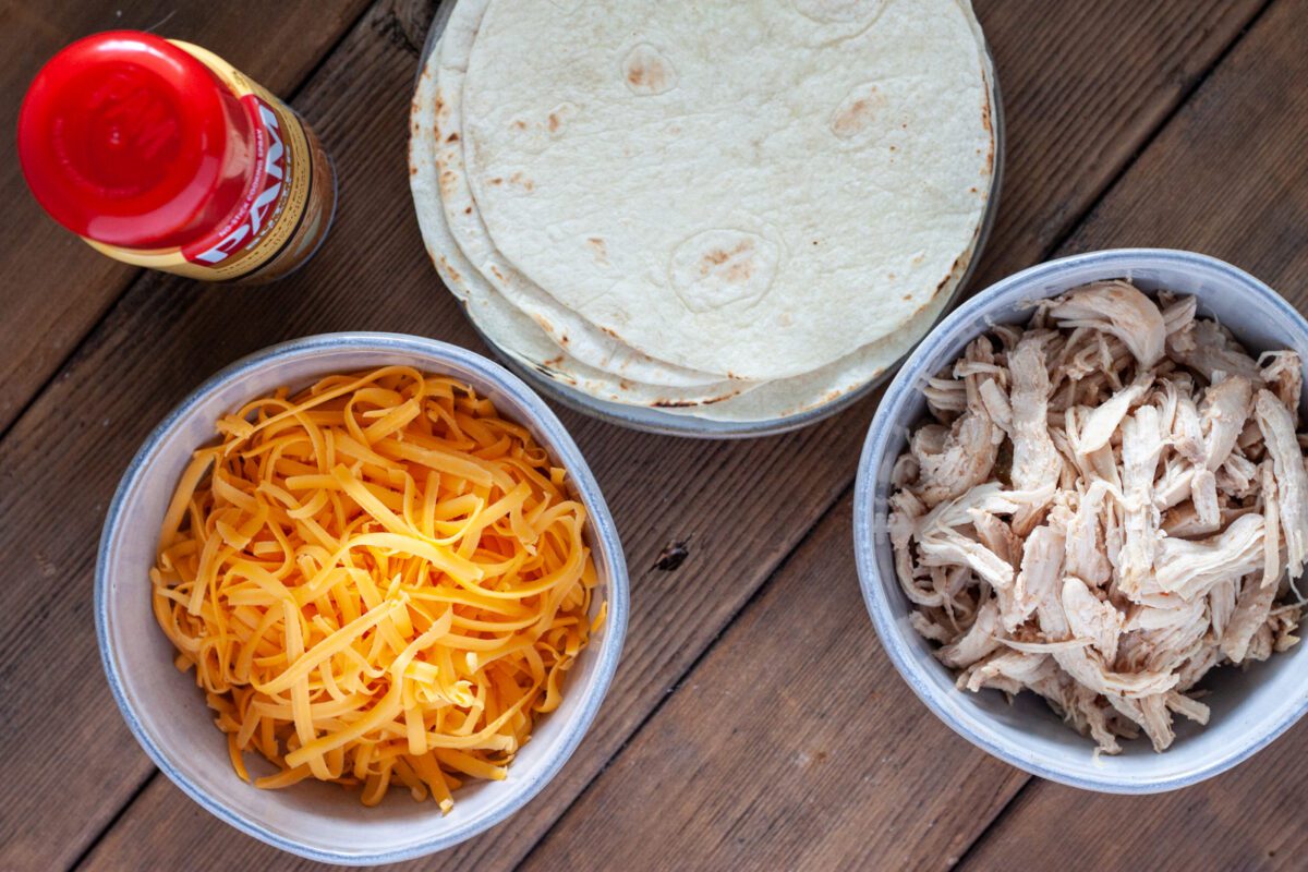Ingredients needed for Air Fryer Tacos, included here are flour tortillas, shredded chicken, and shredded cheese