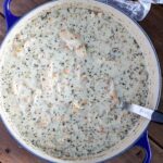 A pot of white chicken chili with cream cheese and porchetta seasoning and a ladle in the bowl.