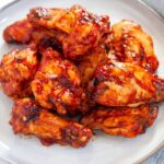 Air fryer frozen chicken wings in a sauce and served on a platter.