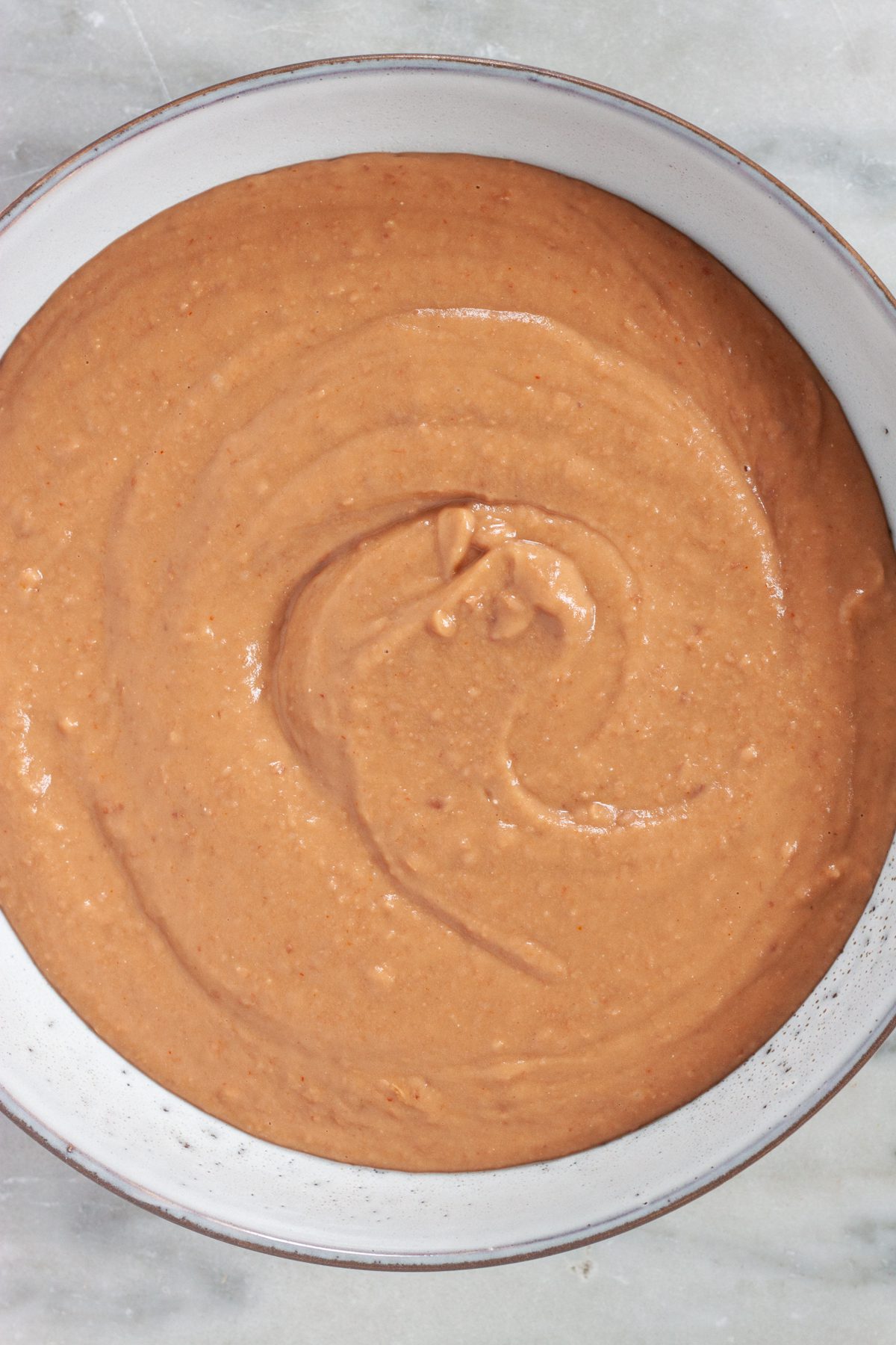 A bowl of restaurant style refried beans on the table.