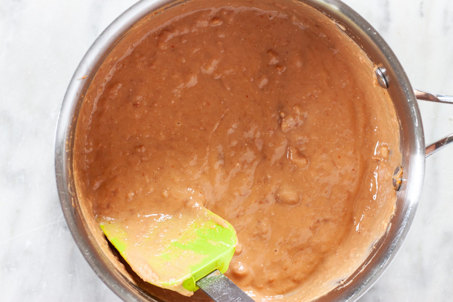 Restaurant Style Refried Beans in a pan after cooking and a spatula to the side.