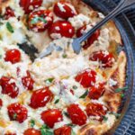 Goat cheese and tomato dip with a spoon in the bowl.