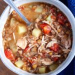 A bowl of turkey lentil soup with a spoon leaning on the edge of the bowl.