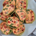 Cream cheese christmas pinwheels stacked up on a plate.