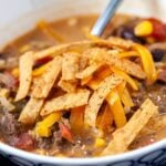 Creamy taco soup in a bowl with tortilla strips on top and a spoon in the bowl.