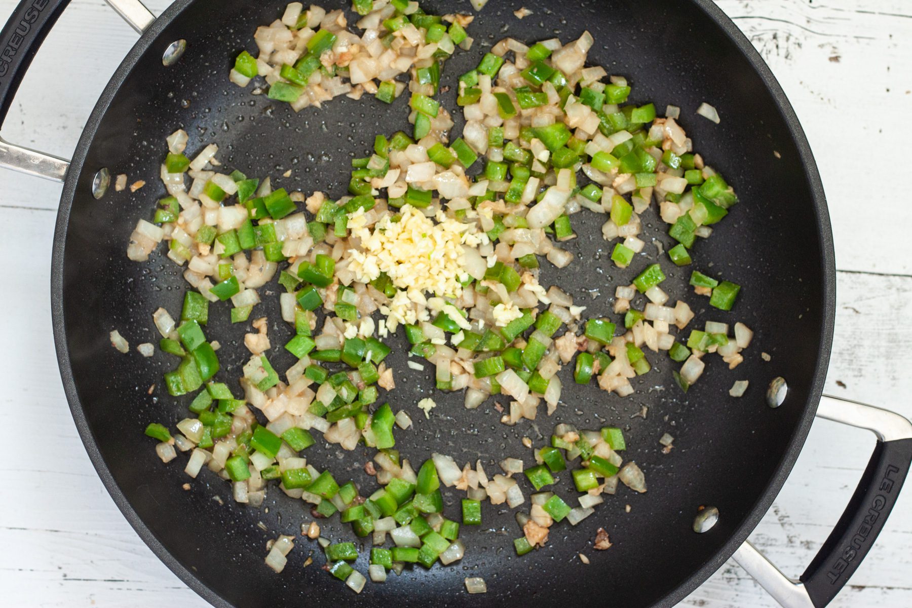 garlic and diced onion and peppers cooking in a pan