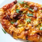 A mini naan pizza topped with prosciutto and jalapenos fresh from the air fryer.