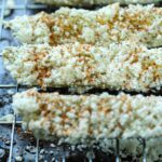 Dill pickle spears treated elote style, covered in crema, cotija, and tajin seasoning.