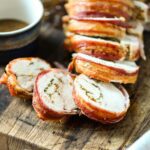 turketta sliced on a cutting board next to a ramekin with turkey gravy.