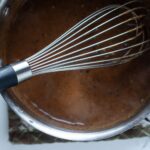 turkey gravy in a saucepan with a whisk.
