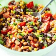 mexican bean salad ready to be eaten in a large green bowl.