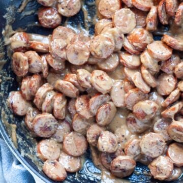 Creamed sliced hot dogs freshly cooked and steaming in a frying pan.