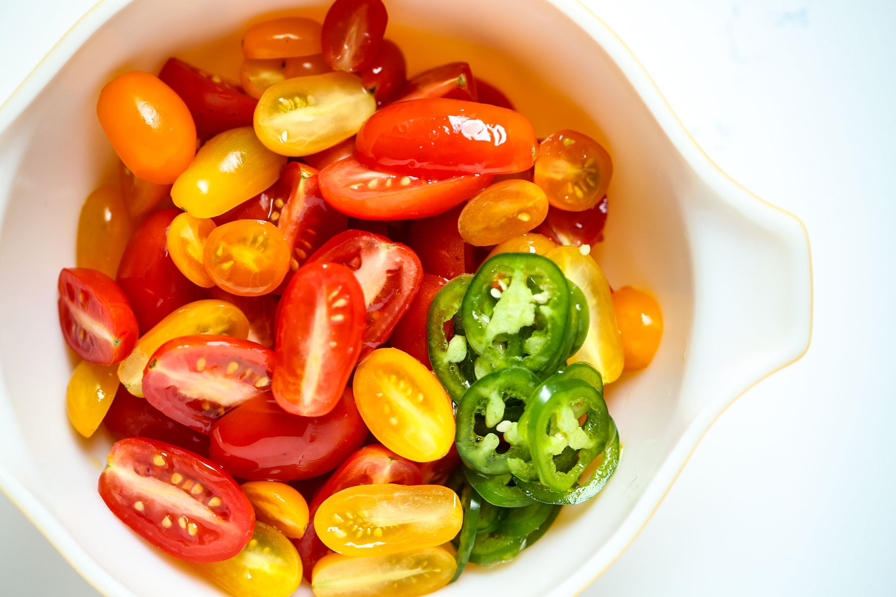 Marinated tomatoes with sliced jalapeno in a serving bowl.
