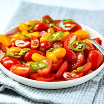 A bowl of marinated tomatoes with thinly sliced jalapenos.