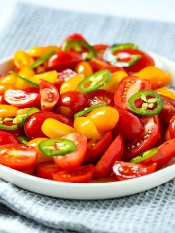 A bowl of marinated tomatoes with thinly sliced jalapenos.