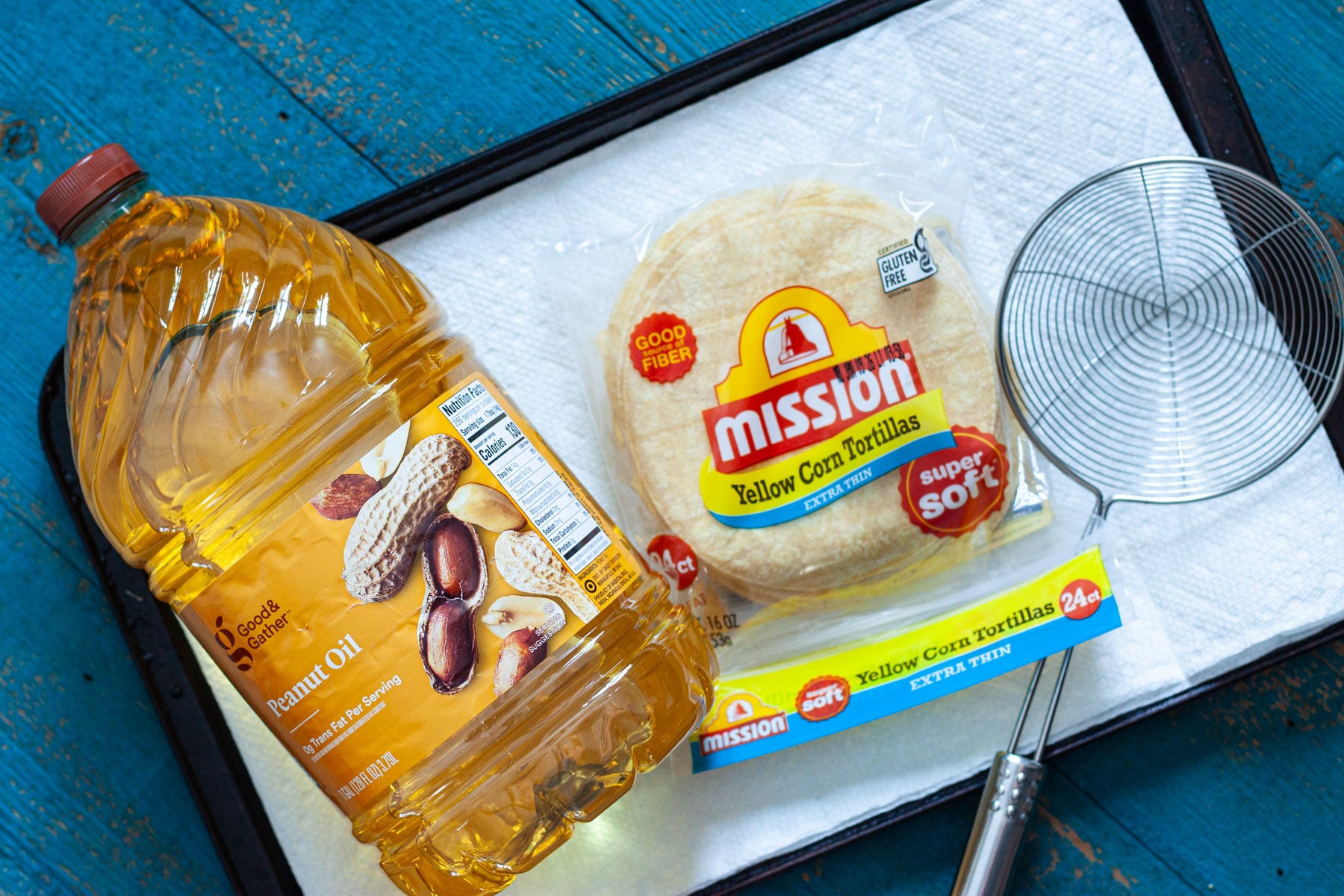 ingredients to make fried tortilla strips, including peanut oil, extra thin corn tortillas and a spider for deep frying