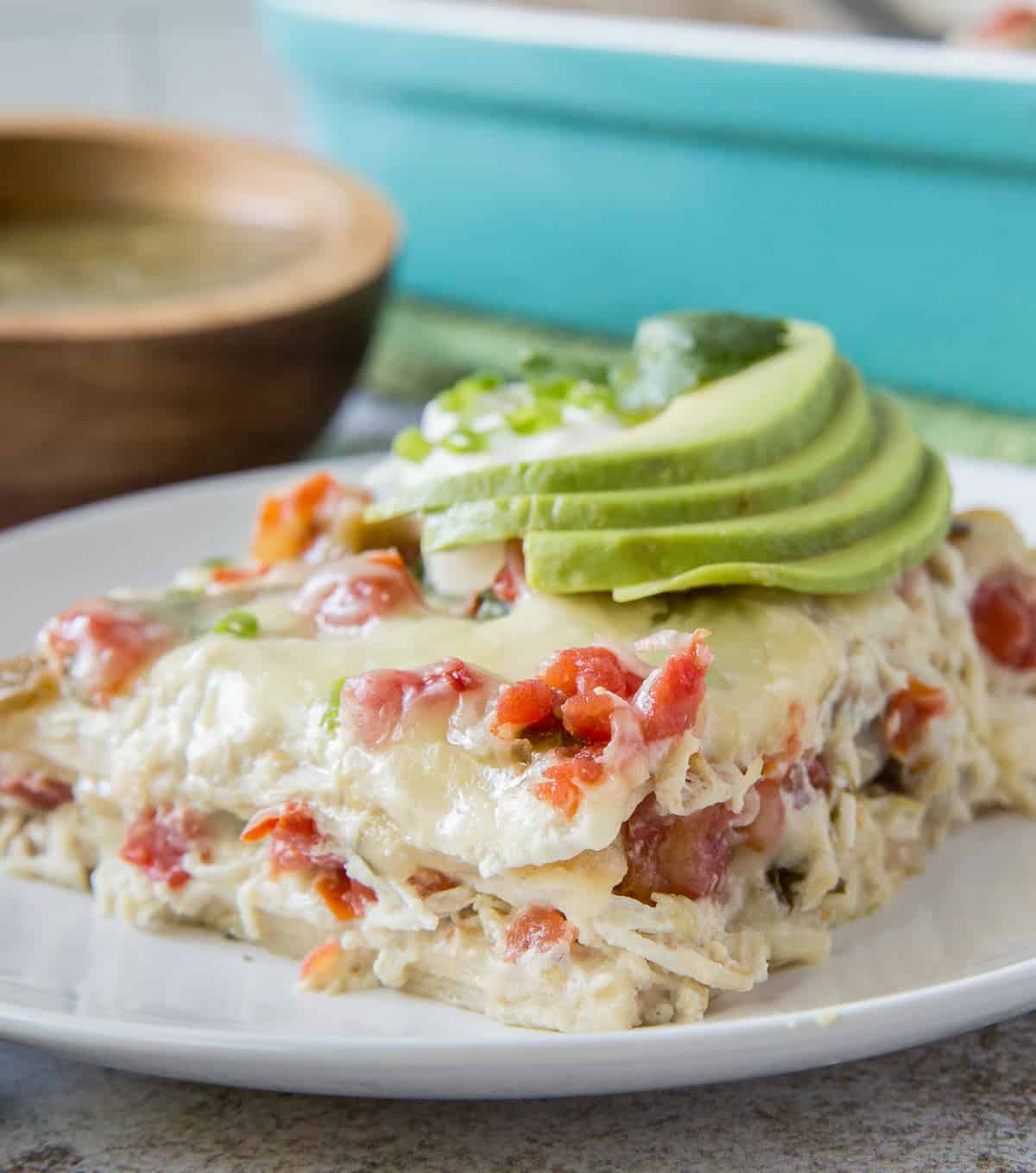 a slice of chicken tortilla casserole on a plate garnished with sliced avocado
