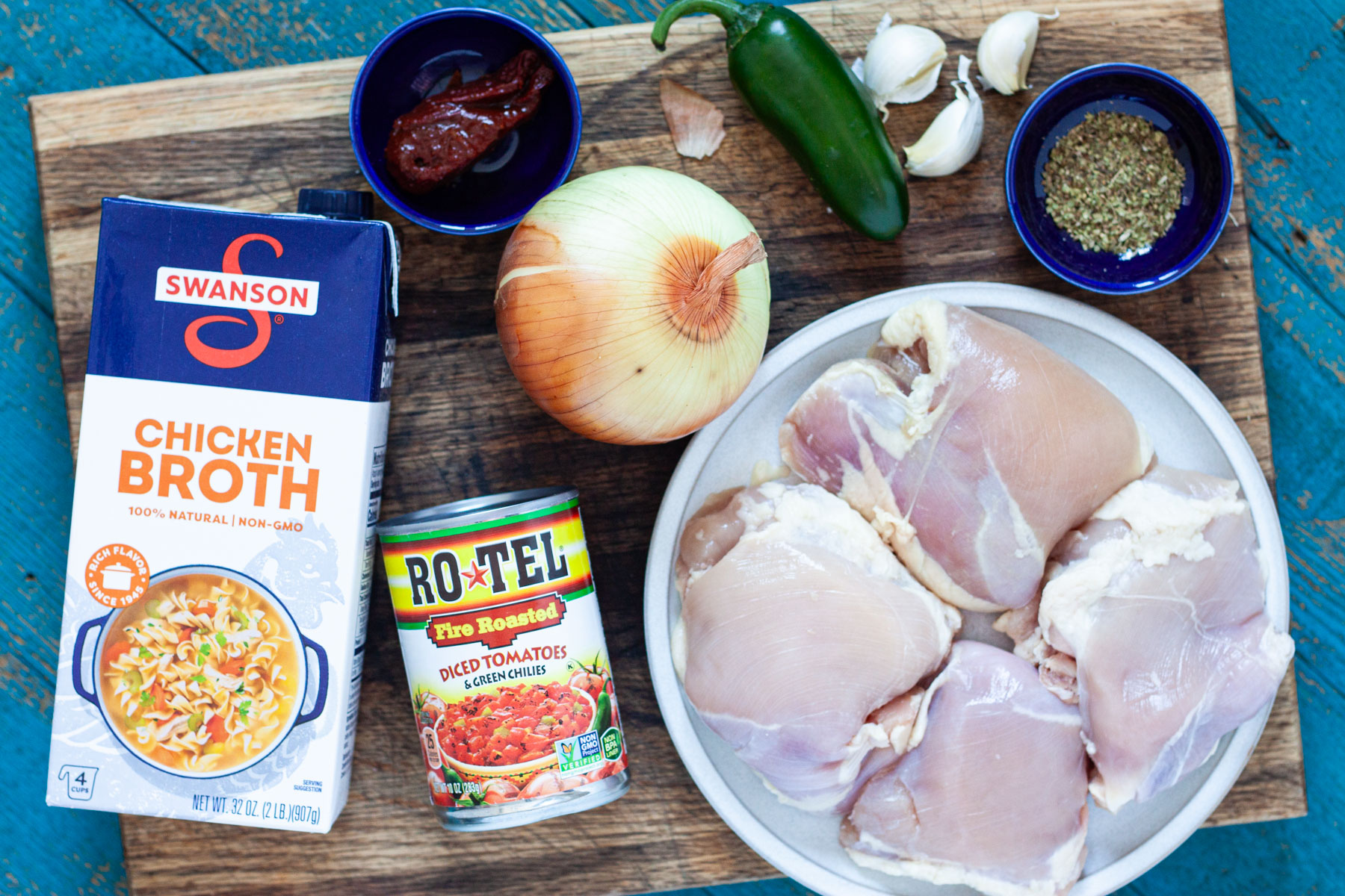 chicken tortilla soup ingredients including chicken thighs, chicken broth, Rotel fire roasted tomatoes, onion, jalapeno, chipotle en adobo, garlic, and oregano.