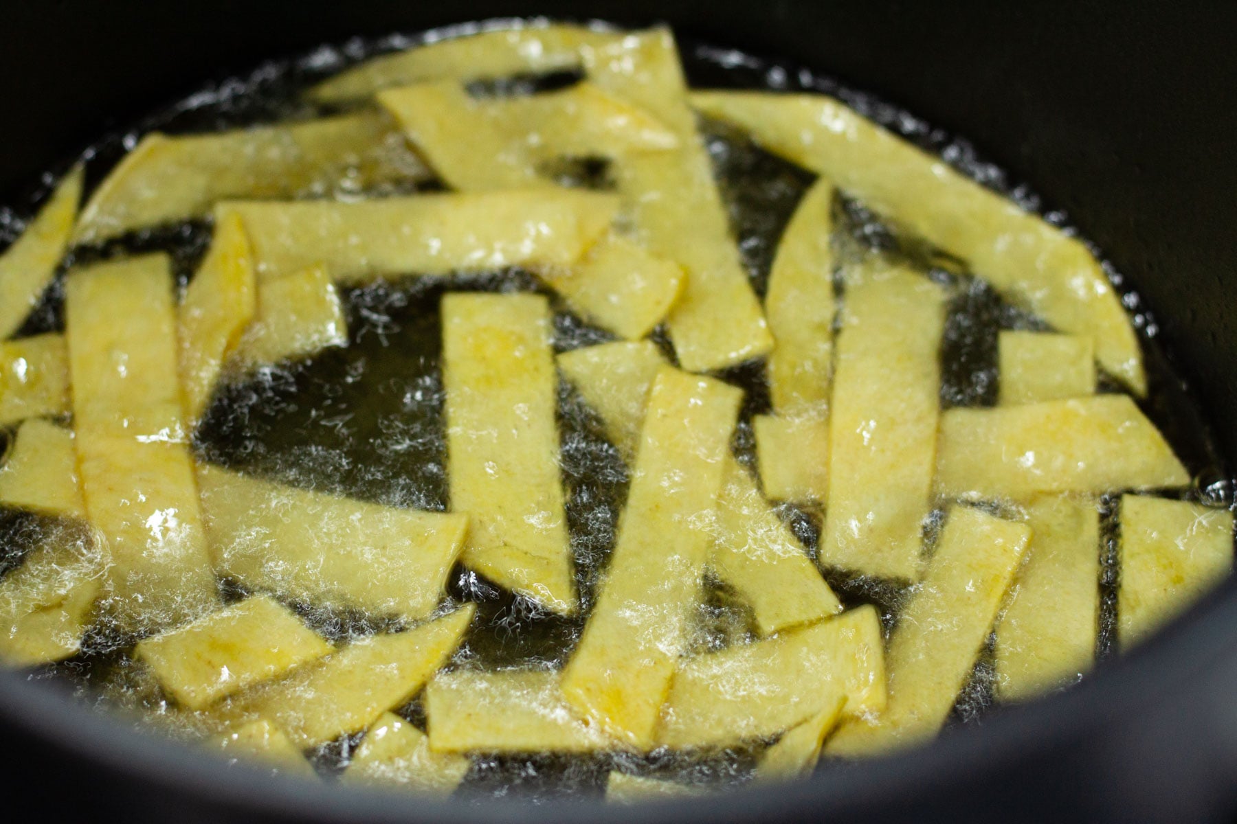 tortilla strips deep frying in oil.