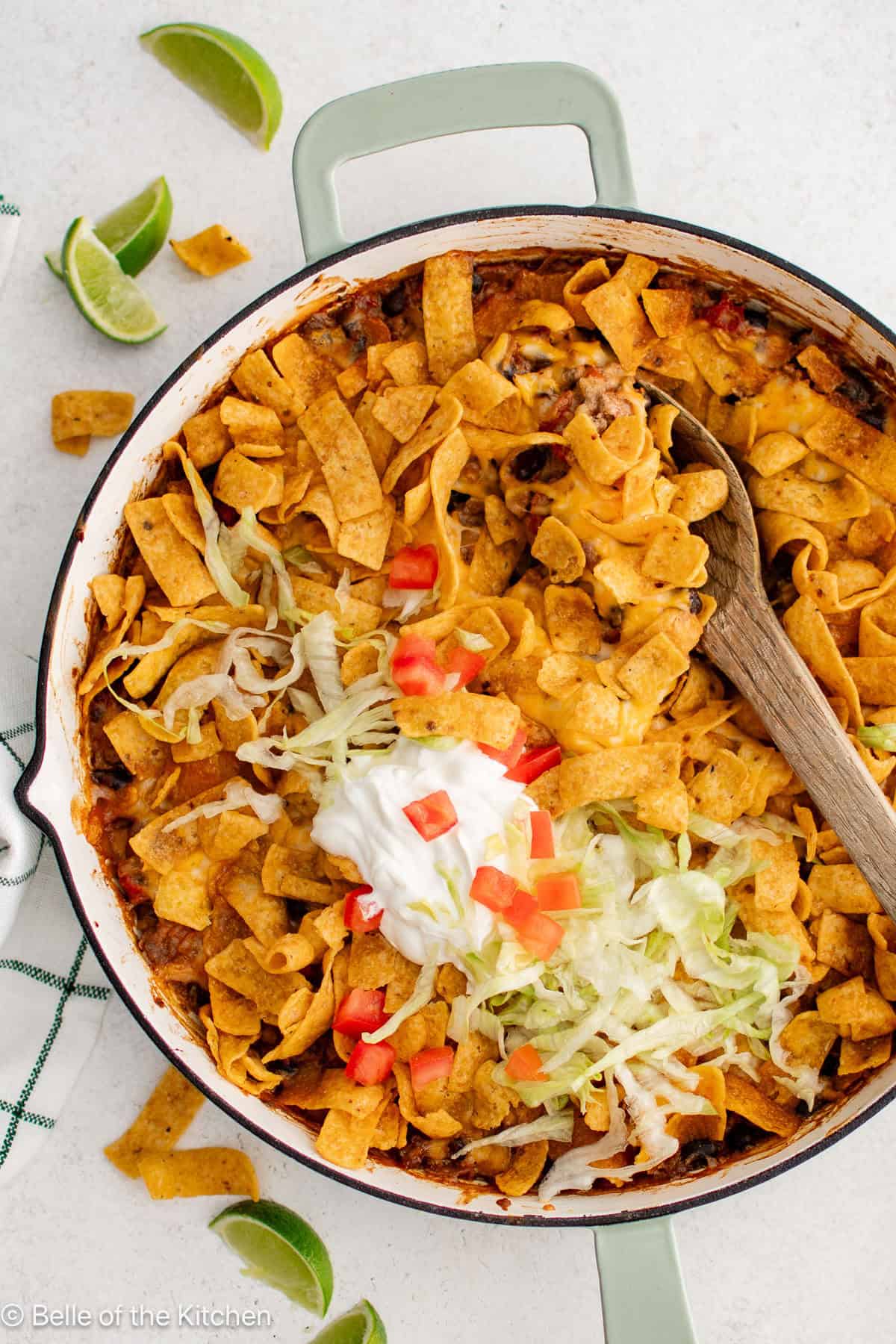 walking taco casserole in a pan and garnished with toppings.
