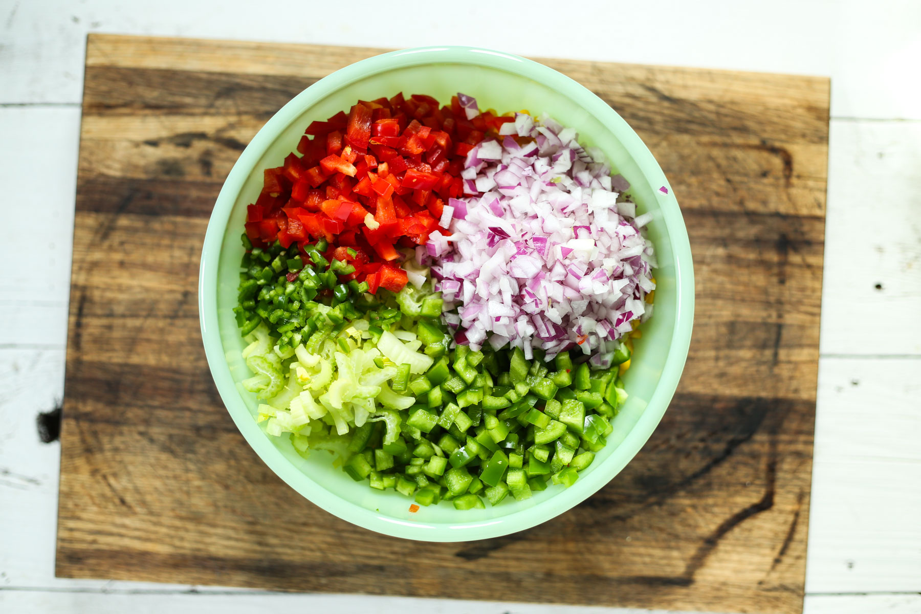 marinated bean salad in a green bowl on a cutting board.
