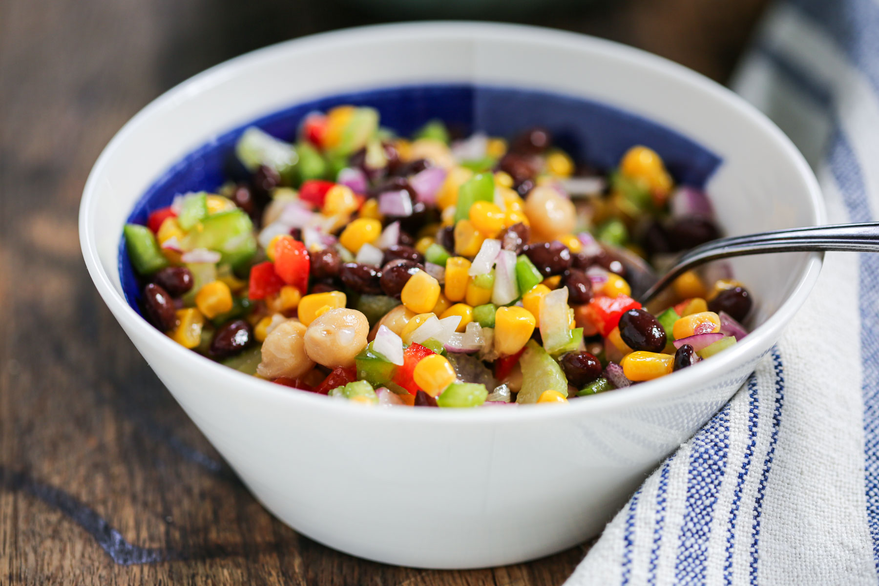 marinated bean salad in a white and blue with a spoon.