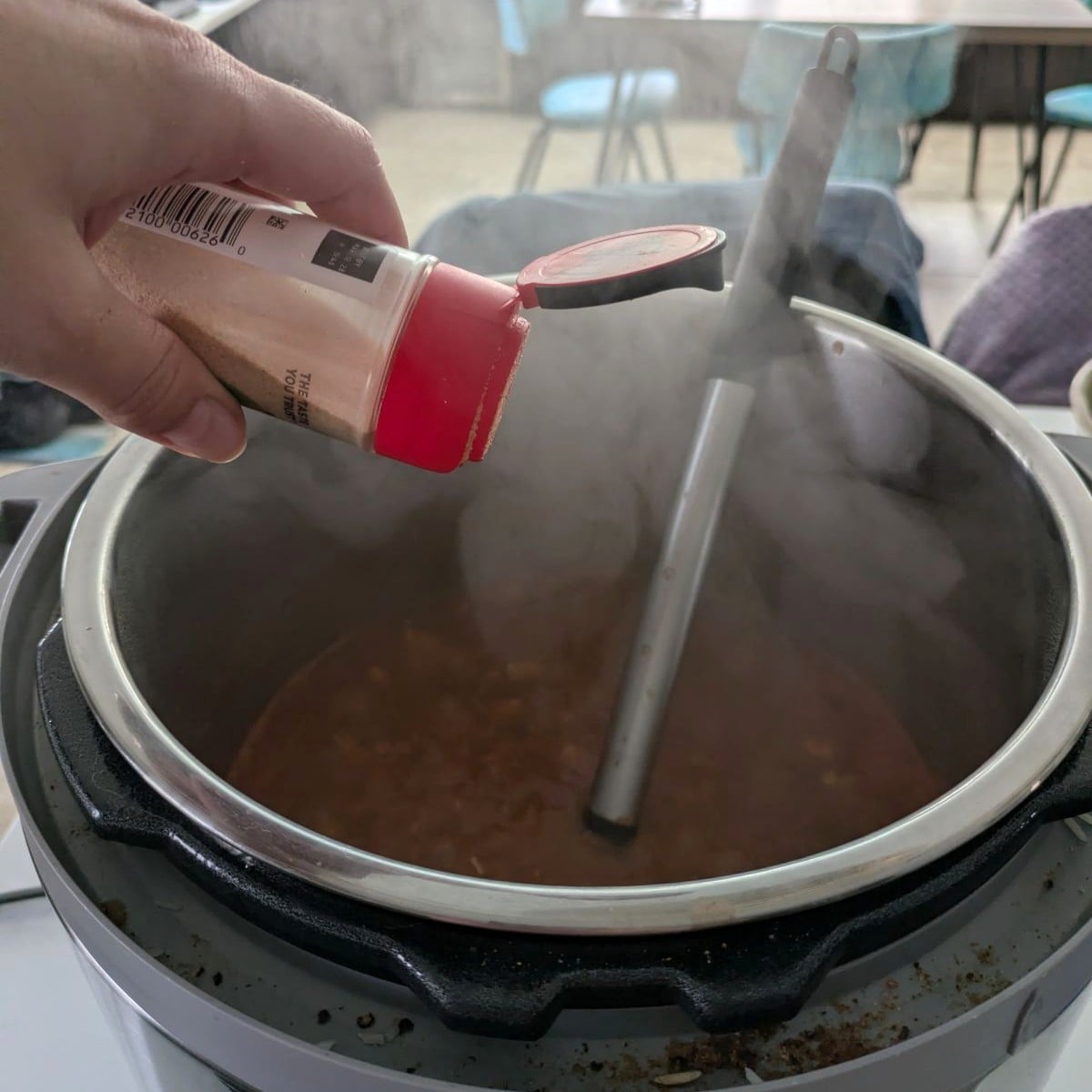 a spice shaker being shaken over food cooking in an instant pot