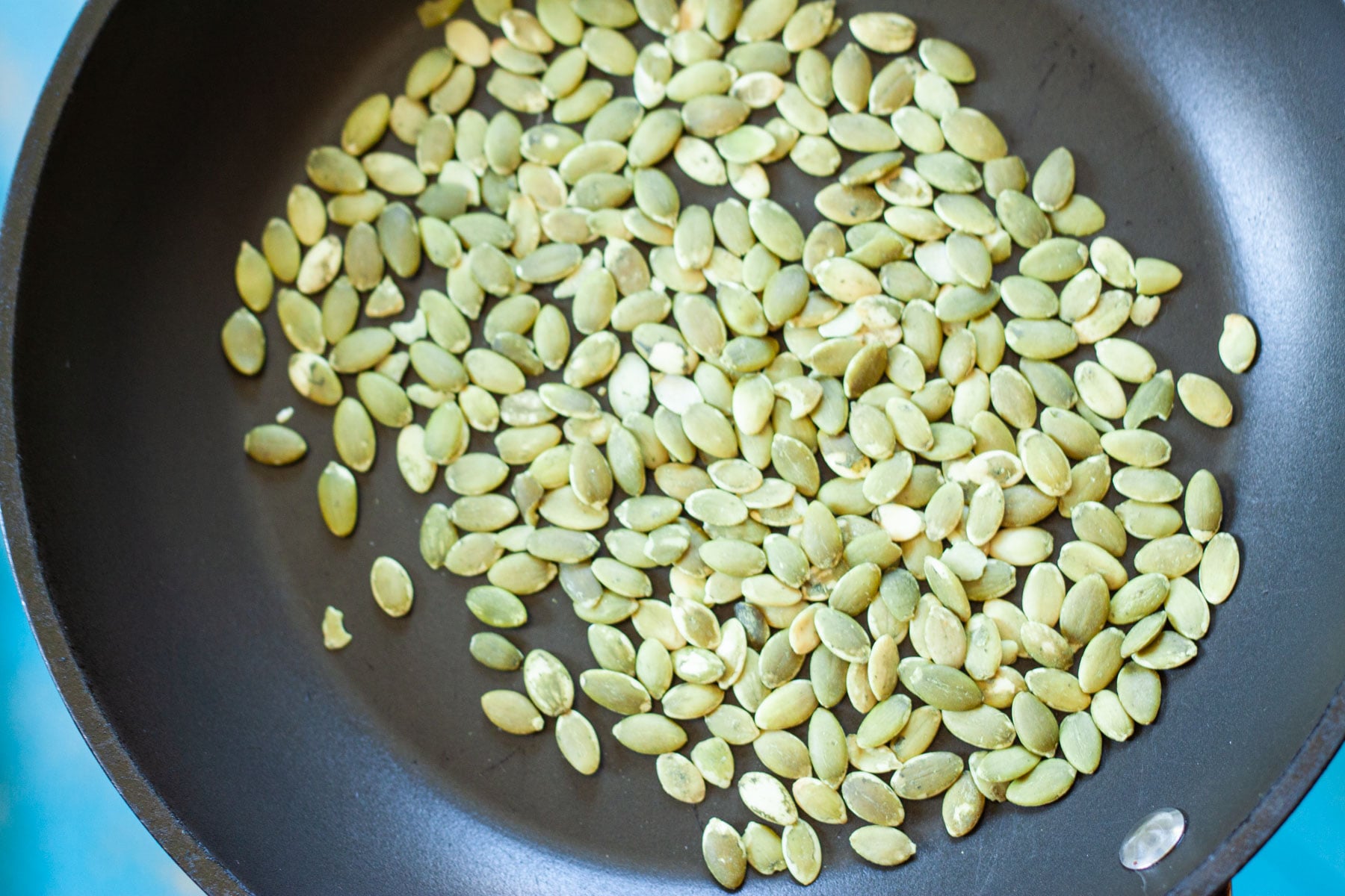 Pepitas toasting in a frying pan.