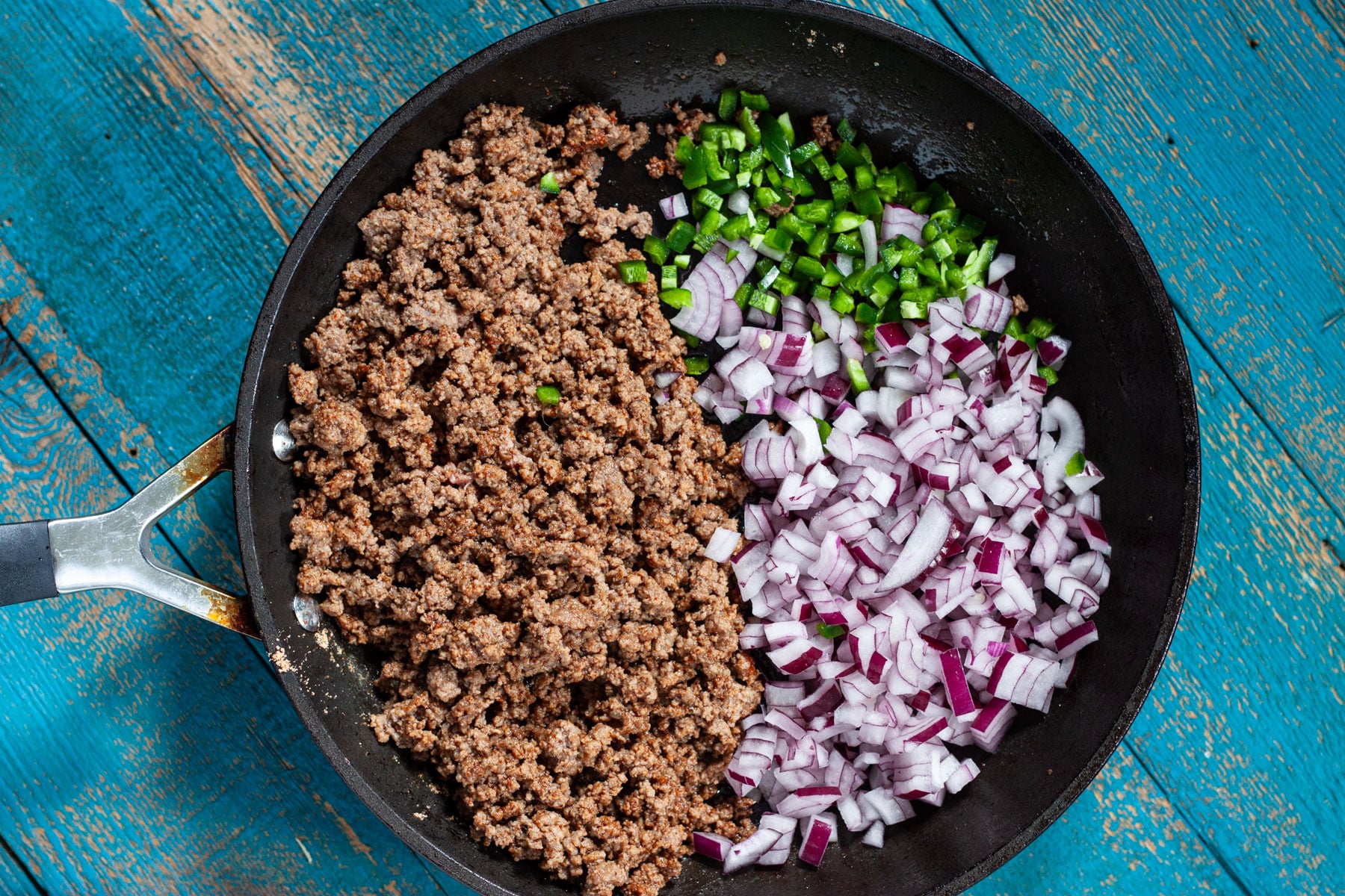 Fresh onion and jalapeno added to the skillet of cooked ground beef.