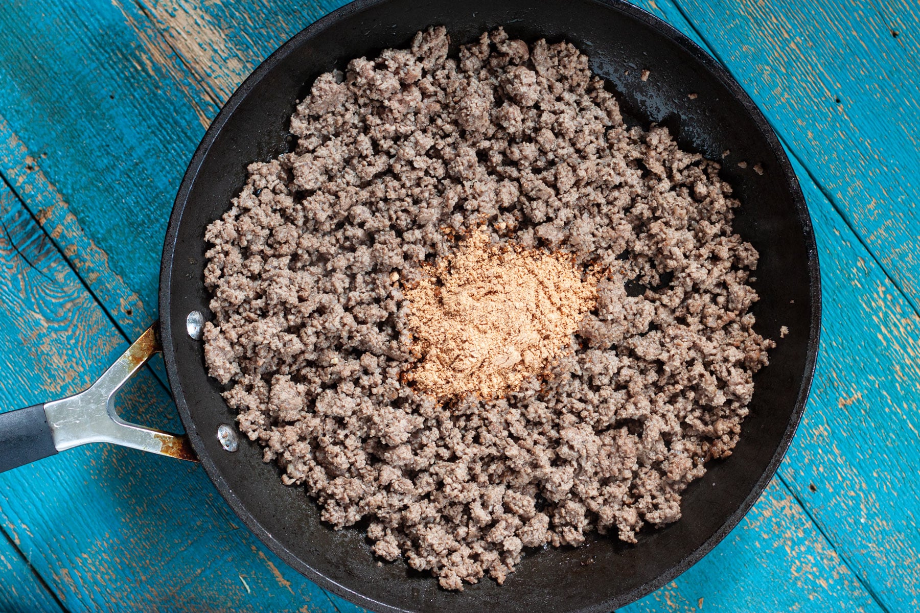 Taco seasoning added to a pan of cooked ground beef.